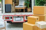 Camión de mudanzas abierto con muebles y cajas en la entrada de una vivienda