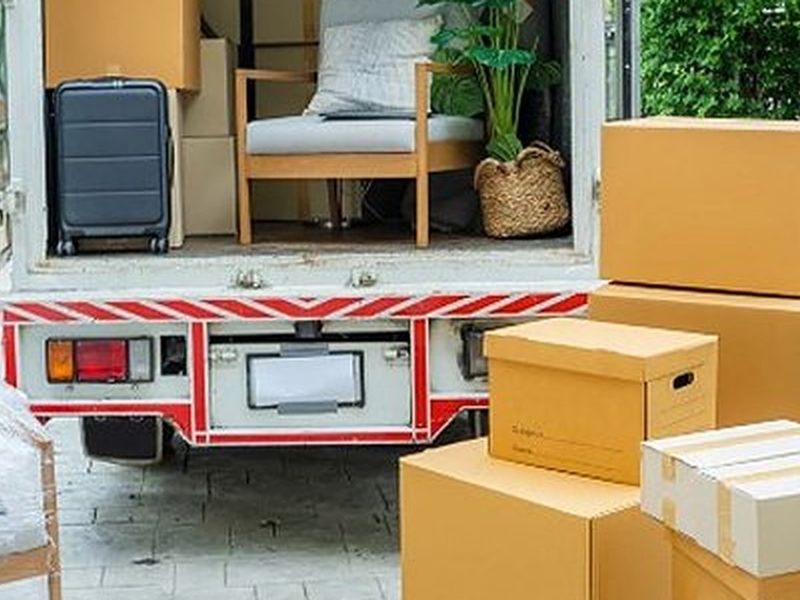 Camión de mudanzas abierto con muebles y cajas en la entrada de una vivienda