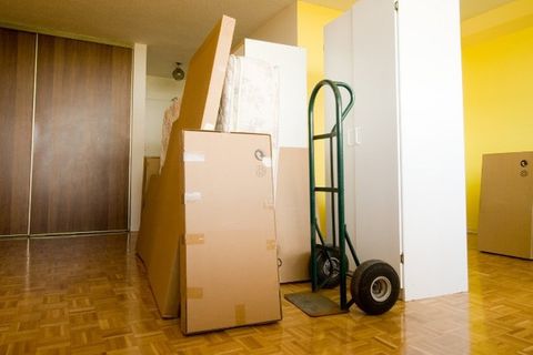 Carretilla de mudanzas junto a armarios y muebles embalados en un pasillo
