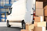Furgoneta de mudanzas con las puertas abiertas y cajas apiladas junto a ella