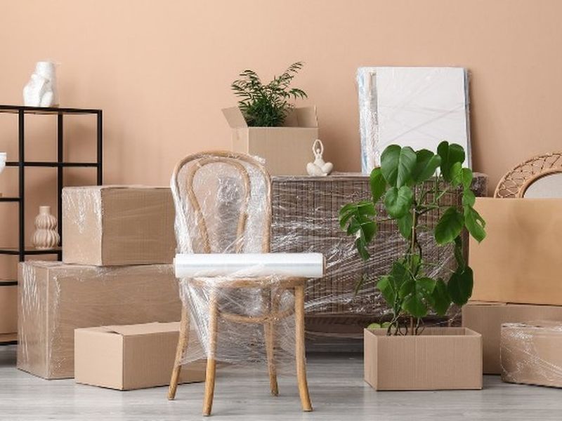 Silla, cuadros y cajas embalados en un salón, preparados para la mudanza