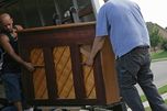 Operarios de mudanzas descargando un piano vertical por la rampa del camión