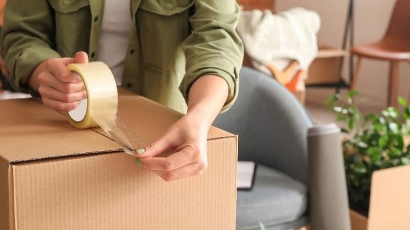 Manos precintando una caja de cartón para la mudanza