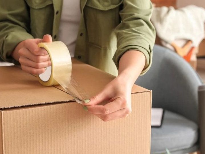 Manos precintando una caja de cartón para la mudanza