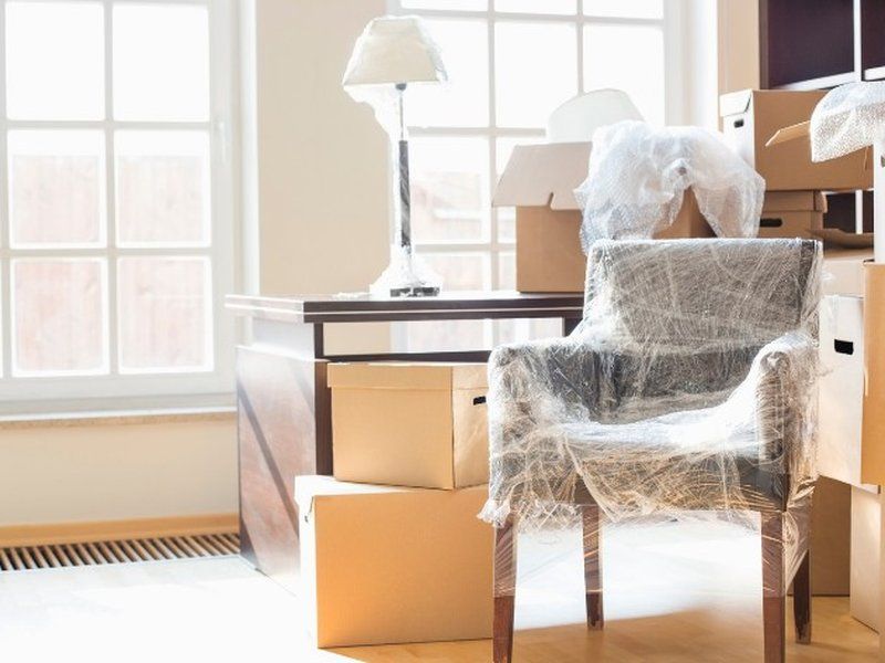 Sillón envuelto en film entre cajas de mudanza junto a una ventana